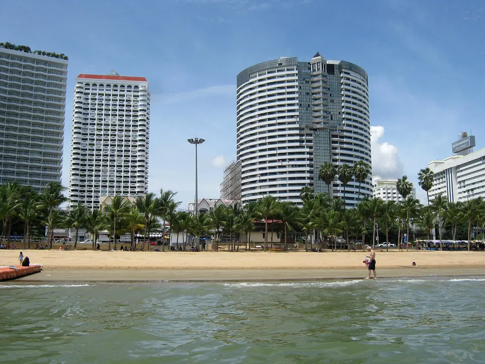 Photo: Jomtien Beach seen from the sea, the sand and a row of palms before tall white condominium towers