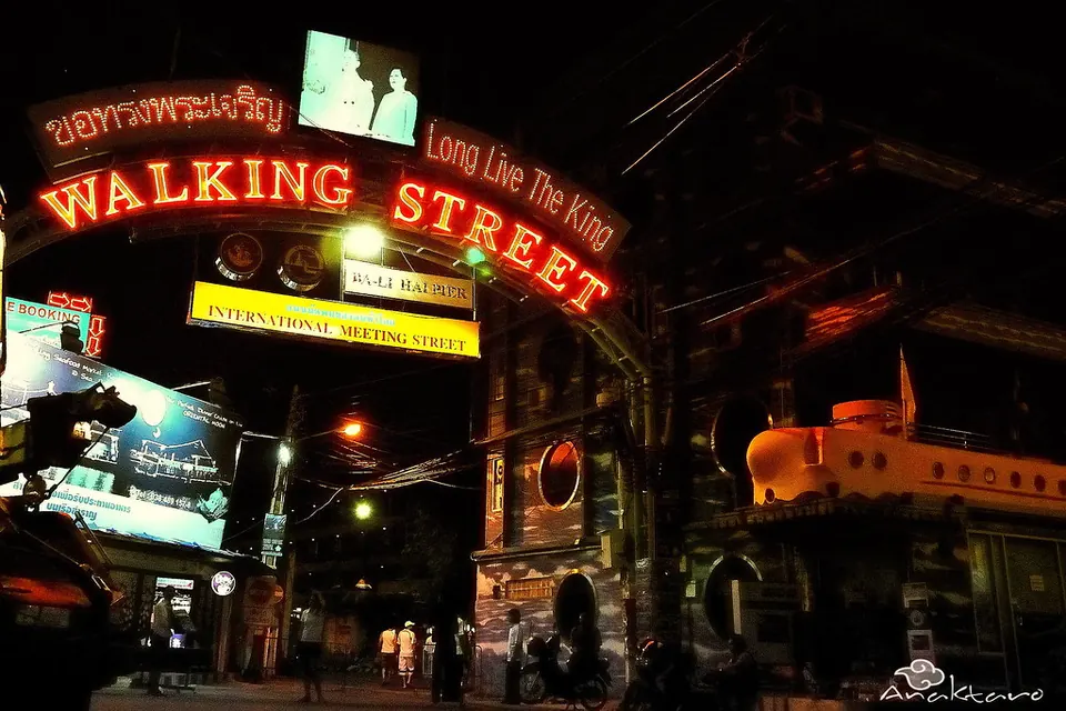 Photo: the neon Walking Street arch at the Beach Road end, lit red at night, with people walking under it